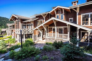 A multi-story lodge with a wooden exterior, a covered porch, and a stone foundation.
