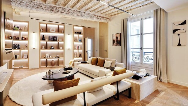 A modern living room with a white sofa, a coffee table, and a bookshelf filled with decorative items. - A LUXURIOUS RETREAT WHERE HISTORY MEETS CONTEMPORARY DESIGN AT RUE DU TEMPLE  (Paris)