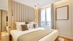 A modern hotel room with a large bed, a bedside table, a mirror, and a view of the outside balcony. - A LUXURIOUS RETREAT WHERE HISTORY MEETS CONTEMPORARY DESIGN AT RUE DU TEMPLE  (Paris)