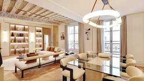 A modern living room with a glass dining table, a sofa, and a built-in bookshelf. - A LUXURIOUS RETREAT WHERE HISTORY MEETS CONTEMPORARY DESIGN AT RUE DU TEMPLE  (Paris)