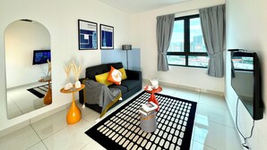A modern living room with a black sofa, a coffee table, a TV, and a large window with curtains.