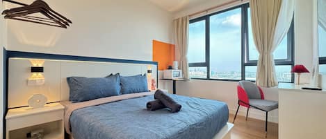 Habitación de hotel moderna con una cama grande, un escritorio, una silla y vistas a la ciudad desde la ventana.