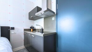 A compact hotel room with a kitchenette, a bed, and a blue door. - Unique apartment with private kitchen and bathroom, inspired by the abstract art of Lena Milius. (Tilburg)