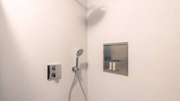 A modern shower with a handheld showerhead and a wall-mounted control panel.