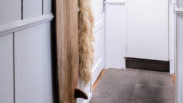 A hallway with a wooden surfboard leaning against a wall, a fluffy rug, and a closed door at the end.