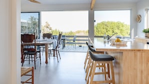 Een moderne keuken met een groot eiland, houten stoelen en uitzicht op de omgeving.