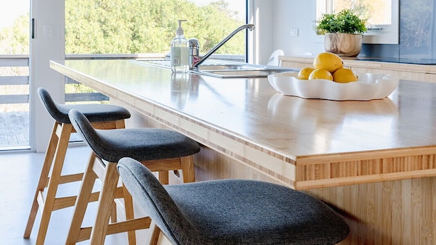 Een moderne keuken met een groot eiland, barkrukken, een spoelbak en uitzicht op groen.