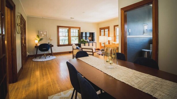 Un comedor con mesa de madera, sillas y un candelabro de vidrio.