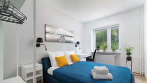Une chambre moderne avec un grand lit, un bureau et une vue sur la verdure par la fenêtre.