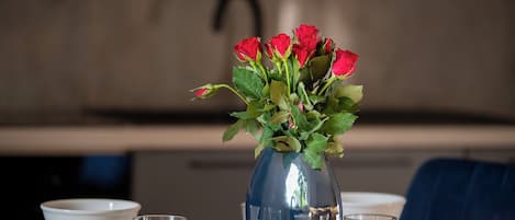 Une table à manger ornée d’un vase de roses rouges, de bols blancs et de verres.