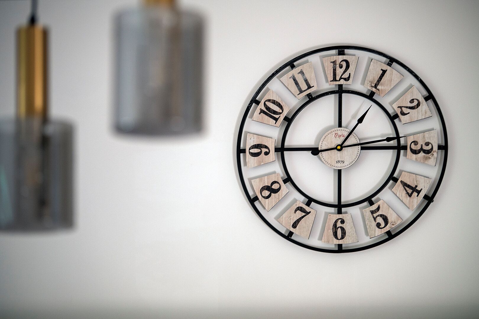 A wall-mounted clock with a circular design and wooden numbers.