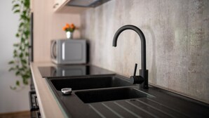 Une cuisine moderne dotée d’un évier noir, d’un plan de travail en acier inoxydable et d’un four à micro-ondes.