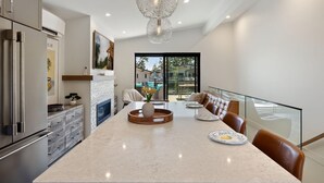 Een moderne keuken met een groot eiland, roestvrijstalen apparatuur en een glazen balustrade met uitzicht op een balkon.