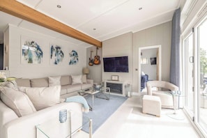 A modern living room with a sofa, coffee table, TV, and artwork on the wall.