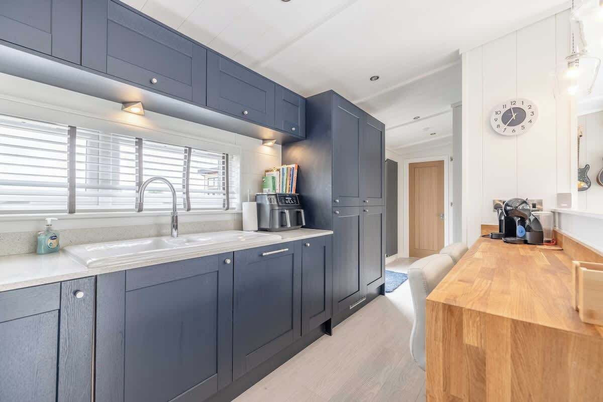 A modern kitchen with dark cabinets, a wooden countertop, and a built-in oven.