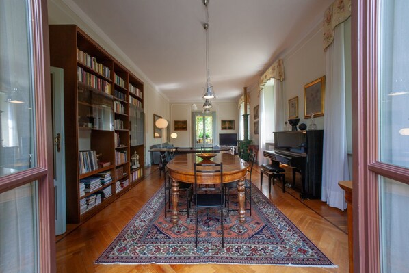 A spacious room with a large wooden dining table, a bookshelf, and a television.