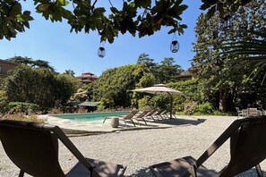 A poolside area with lounge chairs, a pergola, and a clear view of a swimming pool.