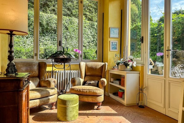 A cozy room with a large window, a leather armchair, a small ottoman, and a bookshelf. - Villa Nanni/pool/parking/central Cernobbio (Cernobbio)