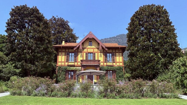 Un grand bâtiment à deux étages, doté d’une façade symétrique, d’une entrée centrale et d’un jardin bien entretenu à l’avant.