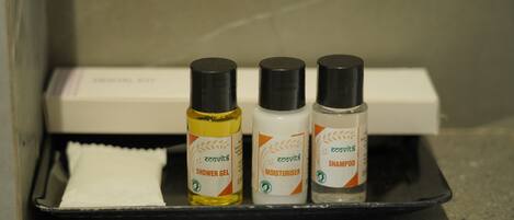 A bathroom shelf with three bottles of shower gel, a bottle of moisturizer, and a white towel.