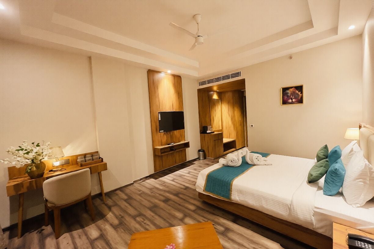 Ein Hotelzimmer mit Bett, Schreibtisch, Stuhl, Fernseher und einem kleinen Tisch.