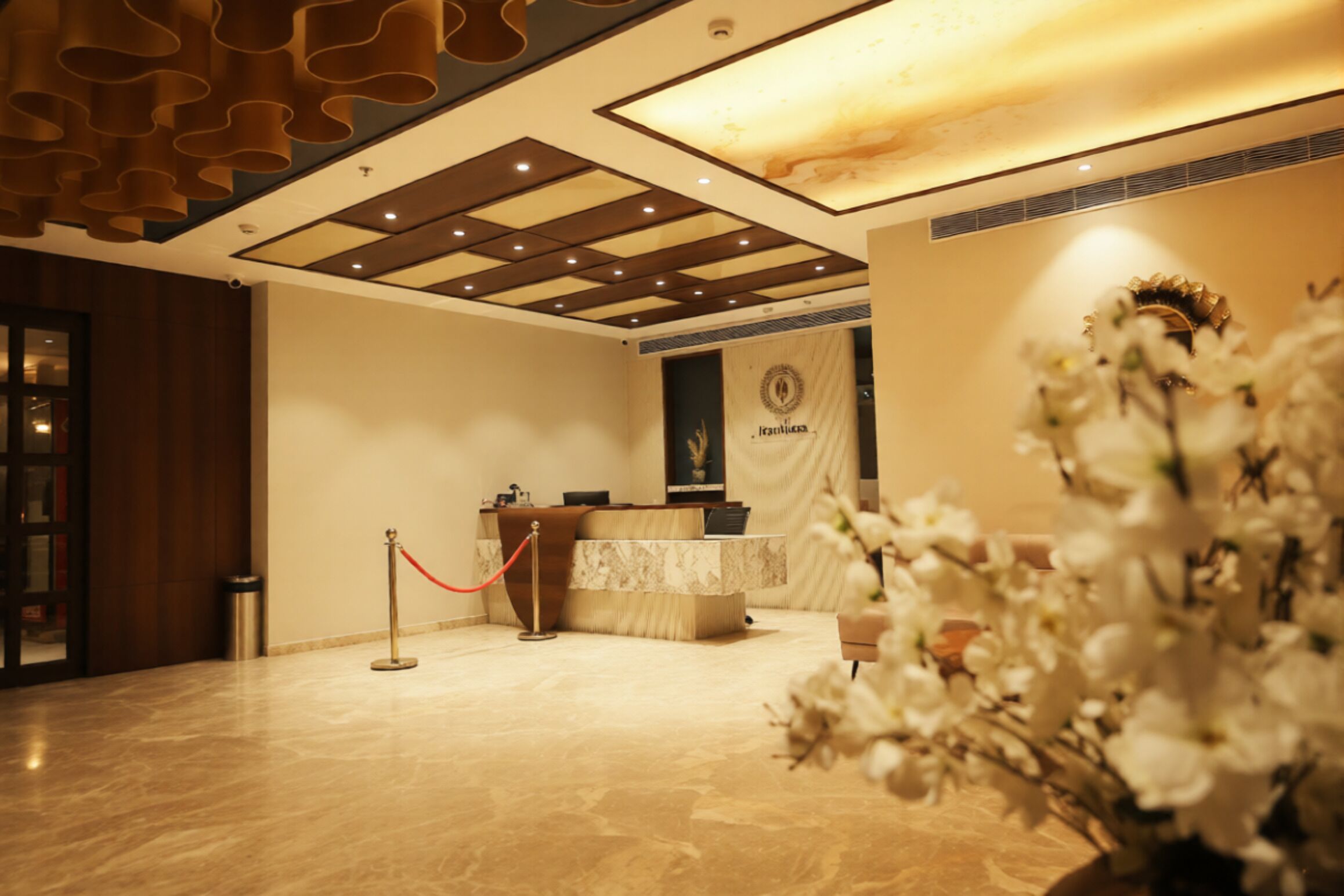 A reception area with a marble floor, a reception desk, a red rope barrier, and a wall with a logo.