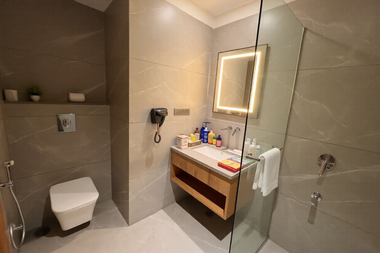 A modern bathroom with a toilet, vanity, and a glass shower enclosure.
