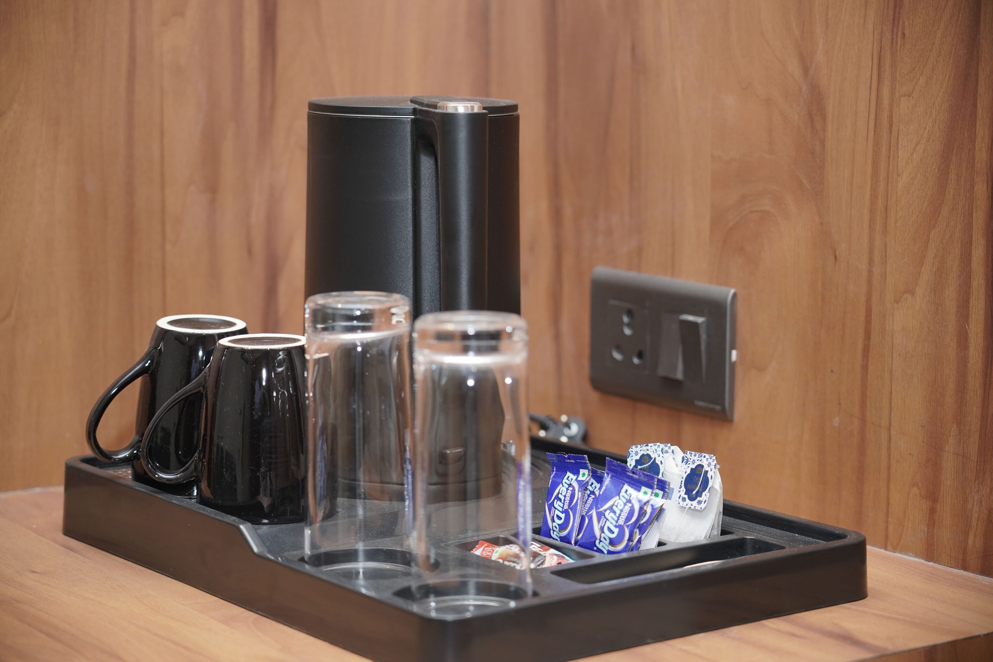 A coffee station with black mugs, a glass carafe, and a coffee machine.