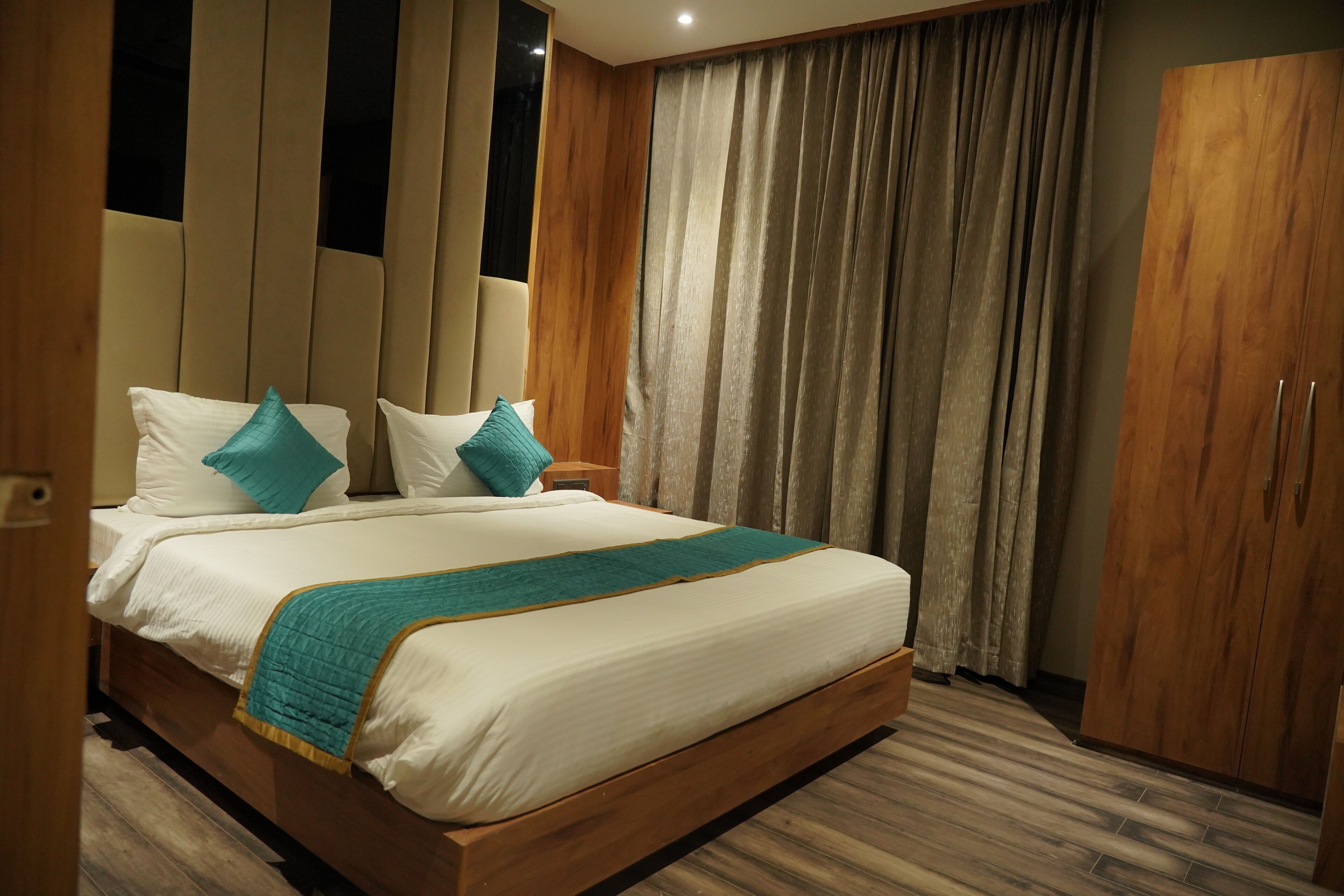 Una cama bien hecha con cabecera de madera, un armario grande y una cortina.