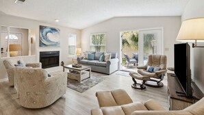 A spacious living room with a fireplace, a sofa set, and a television. - The Blue Whale - Just Blocks to the Beach (Fernandina Beach)