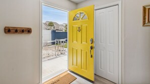A yellow door with a white door beside it, a wooden coat rack, and a doormat. - The Blue Whale - Just Blocks to the Beach (Fernandina Beach)