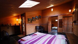 Una habitación con una cama, un escritorio y una silla. Hay cuadros en la pared y una ventana con vistas al exterior.