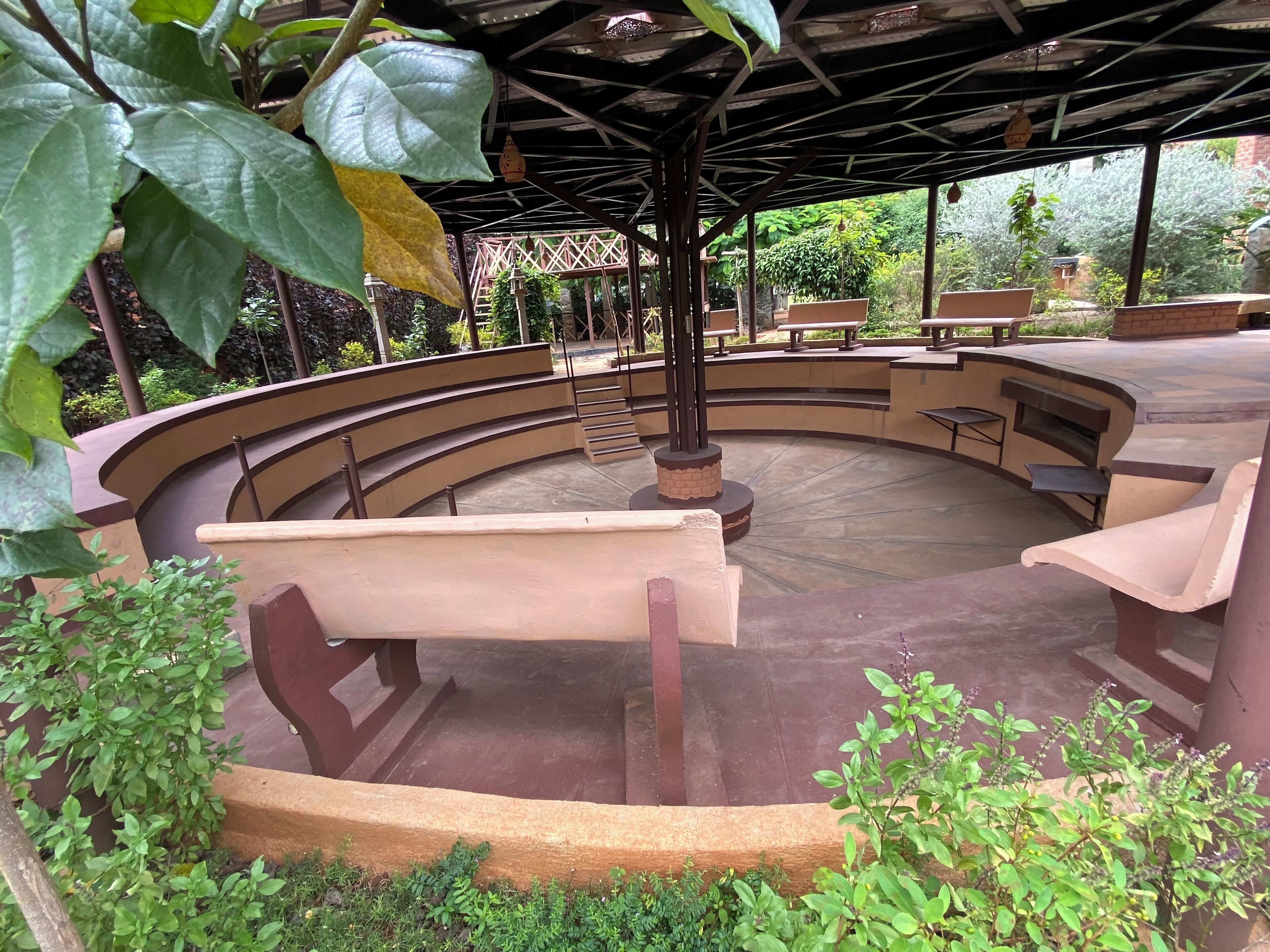 Un espacio de estar al aire libre, circular, con bancos y un pilar central.