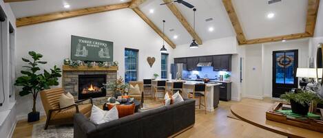Un salón espacioso con chimenea, un sofá y una zona de comedor con una cocina al fondo.