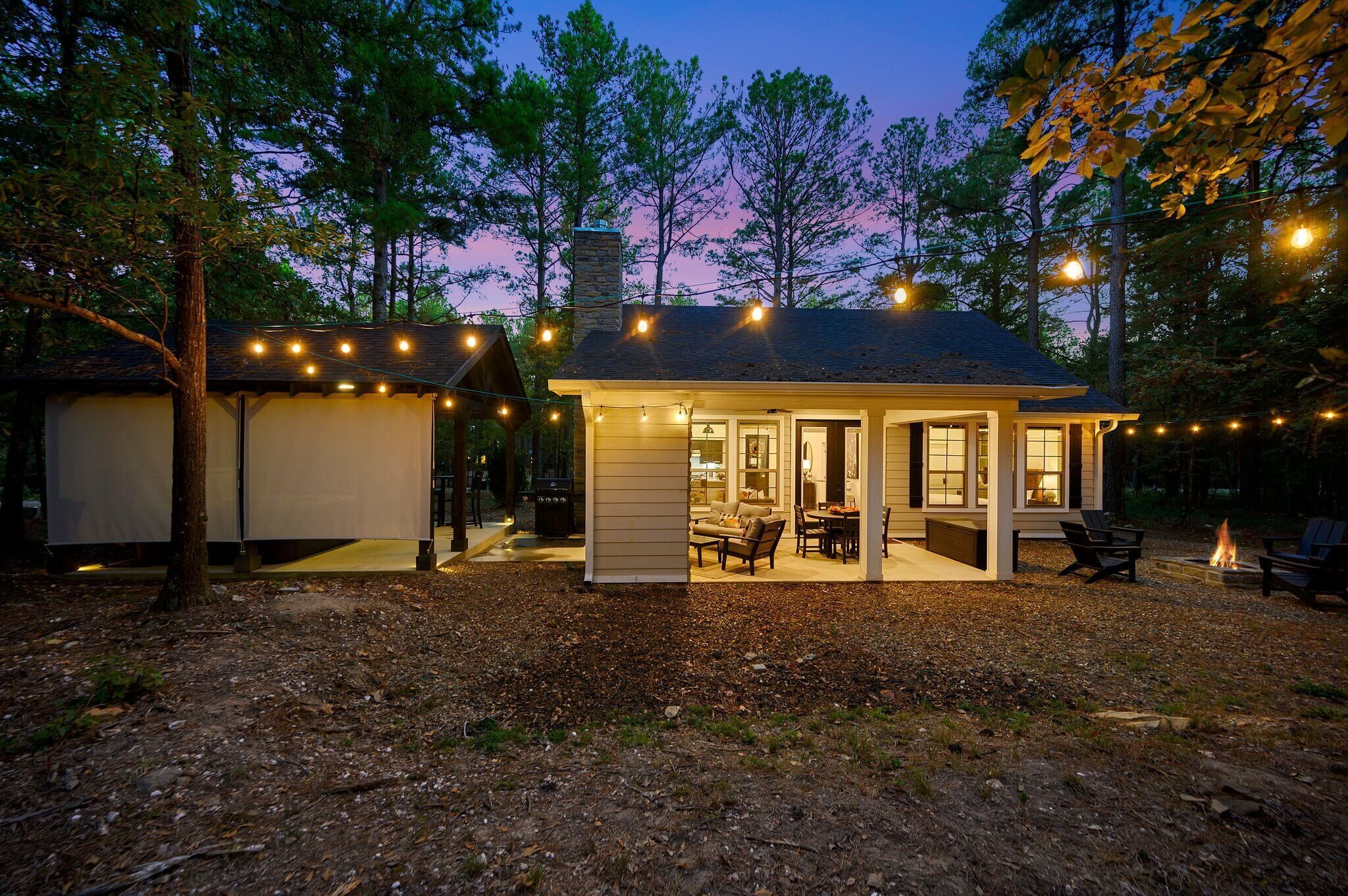 Ein gemütliches Blockhaus mit überdachter Terrasse, Feuerstelle und Lichterketten.