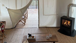 Una tienda de campaña con un interior acogedor que incluye un sofá, un perro, una mesa con una taza y un estufa de leña.