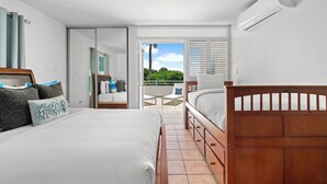 A bedroom with a bed, a wooden headboard, a wardrobe, and a sliding glass door leading to a balcony with a view of greenery. - Retiro del Sol | Your Perfect Caribbean Getaway (Dorado)