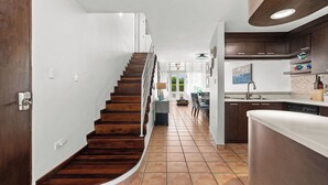 A modern kitchen with wooden cabinets, a white countertop, and a tiled floor. - Retiro del Sol | Your Perfect Caribbean Getaway (Dorado)