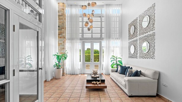 A spacious living room with a white sofa, a coffee table, and a large window with curtains. - Retiro del Sol | Your Perfect Caribbean Getaway (Dorado)