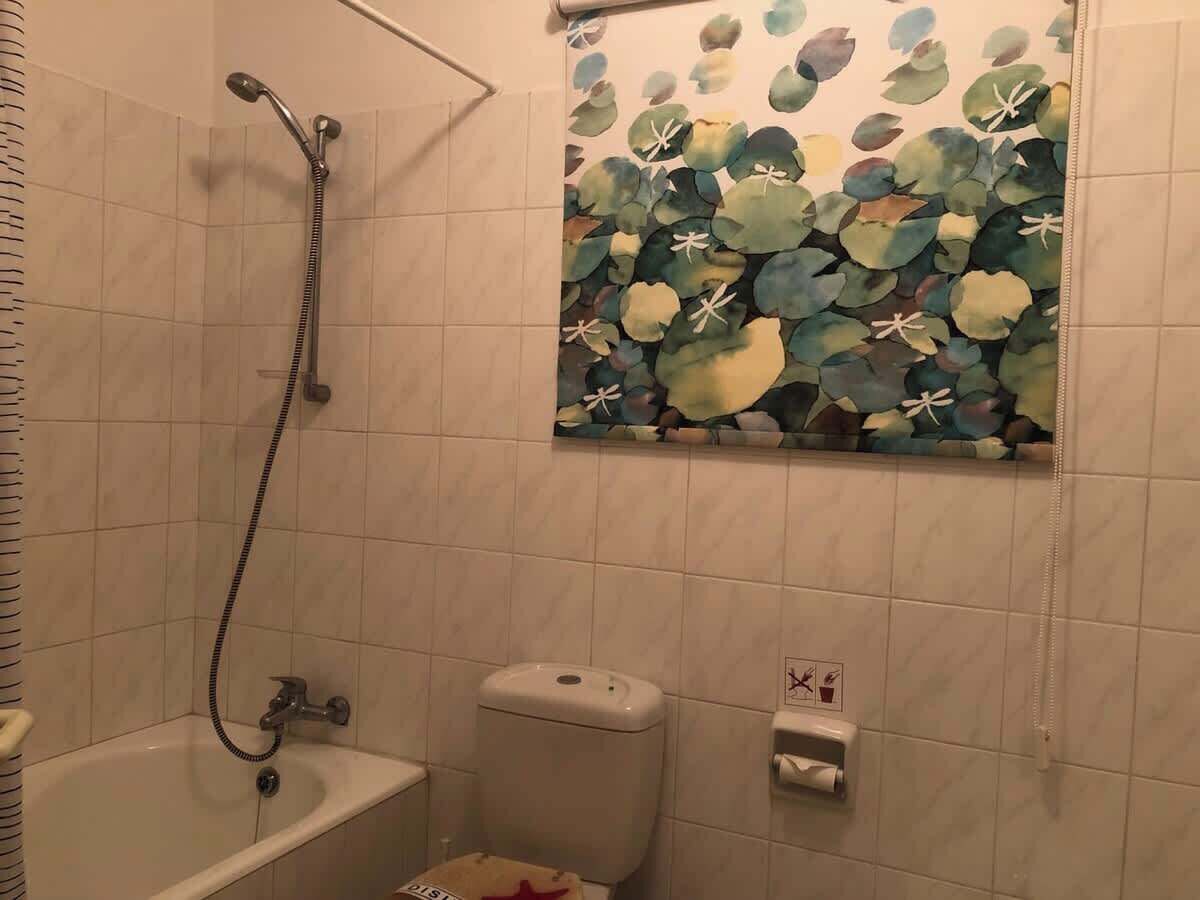 A bathroom with a shower, toilet, and a wall-mounted sink.
