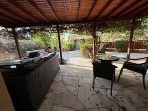 An outdoor patio with stone flooring, a wicker sofa, a round table, and two chairs. - Regina Gardens - Spacious, 3BR, Ground Floor Apart. with Huge Patio (Paphos)