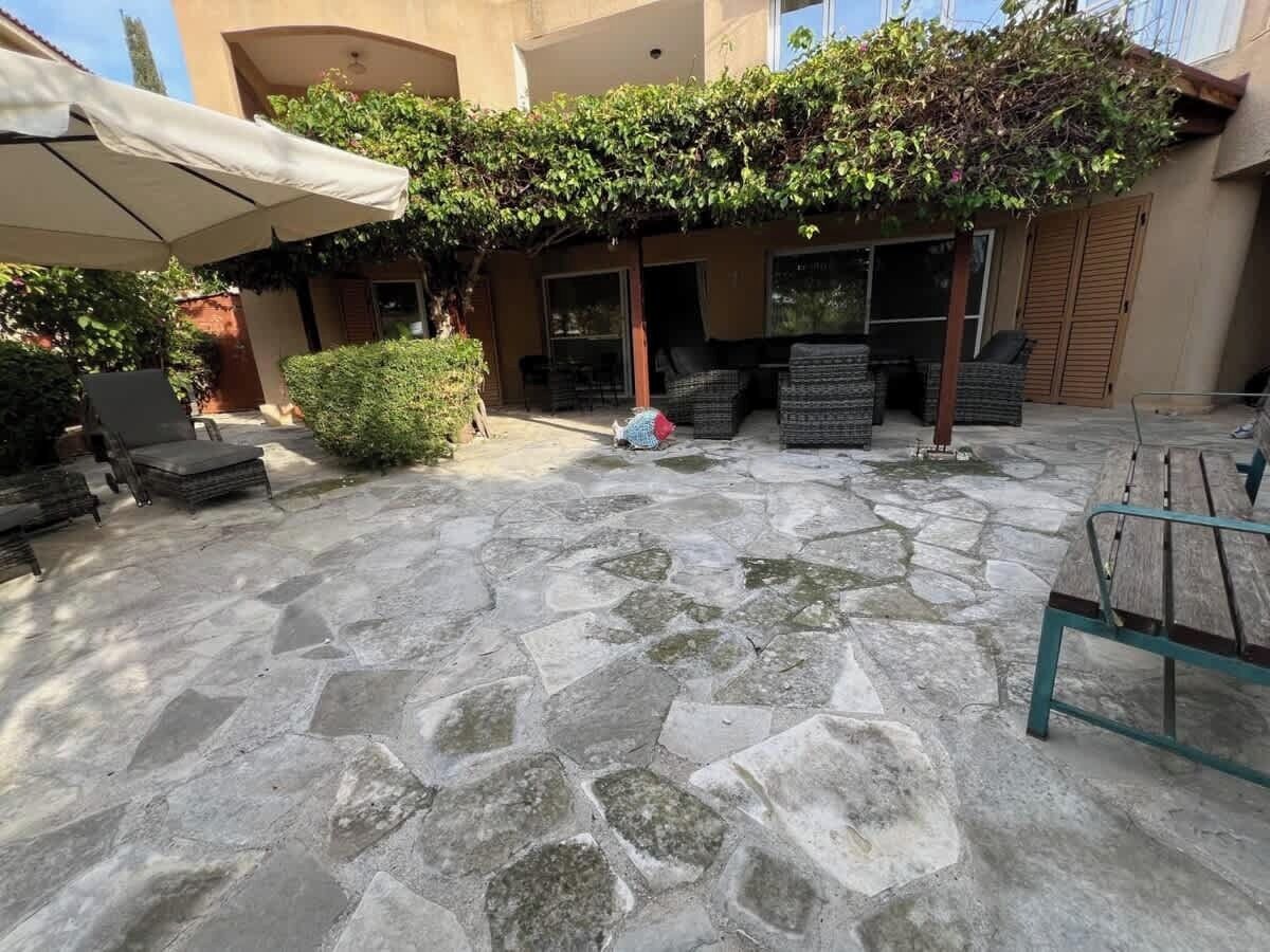 An outdoor patio with stone flooring, wicker furniture, and a covered seating area.