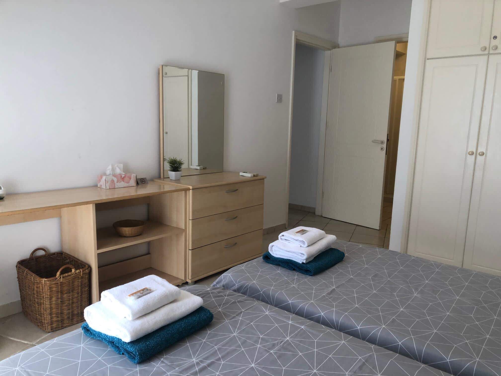 Ein Schlafzimmer mit zwei Betten, einem Holztisch, einem Spiegel und einem Kleiderschrank.