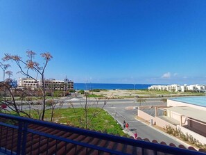 Zona residencial con vista despejada al mar, un estacionamiento y un edificio que dice 'Venus Beach'.