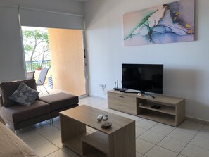 A modern living room with a sofa, coffee table, TV, and artwork.
