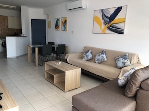 A modern living room with a sofa, coffee table, and dining area.