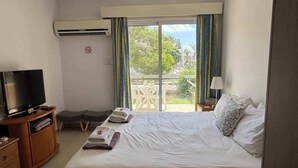 Une chambre d’hôtel avec un lit, une télévision, un bureau et un balcon offrant une vue.