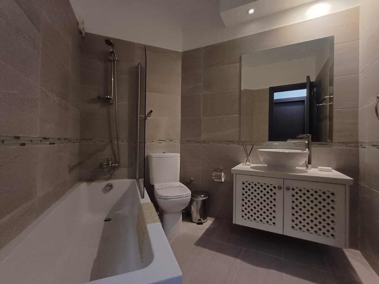A modern bathroom with a bathtub, toilet, and vanity with a mirror.