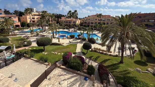 Et resort med flere swimmingpools, palmer og en klar himmel.