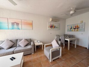 Una sala de estar con sofá, sillón, mesa de comedor y obras de arte en las paredes.